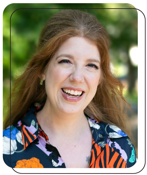 Alison Knott smiling while her hair sways in the breeze. She is outside wearing a bright multipatterned blouse.