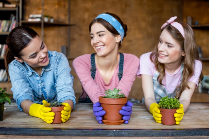 three women admiring each others potted plants